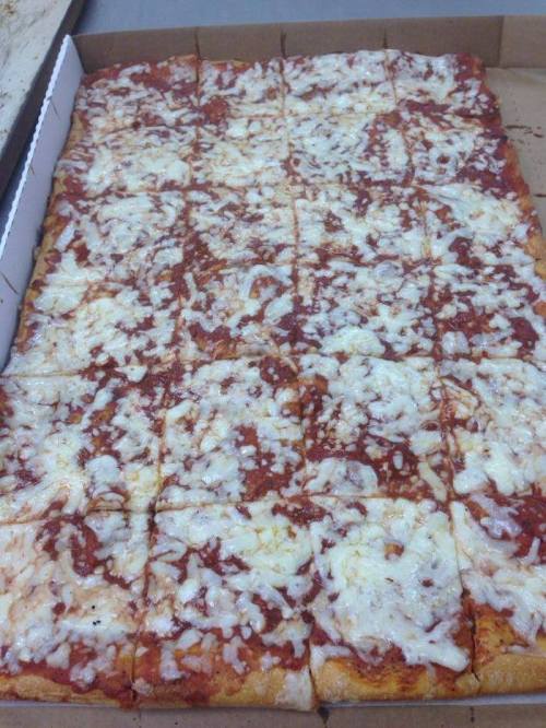 A rectangular pizza with a thick layer of melted cheese and tomato sauce, cut into square slices.