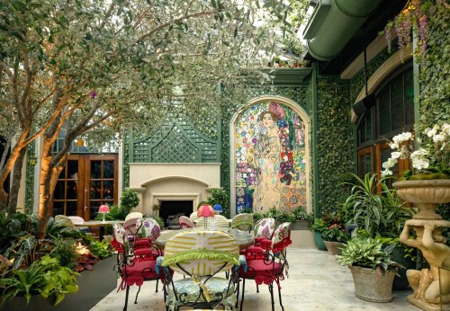 A lush indoor garden with a colorful mural, elegant seating, and greenery creating a serene atmosphere.