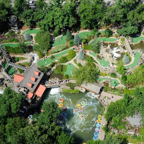 Aerial view of a vibrant amusement park with mini-golf, water rides, and lush greenery.
