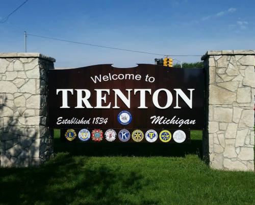 Welcome sign for Trenton, Michigan, established in 1834, featuring various local organization emblems.