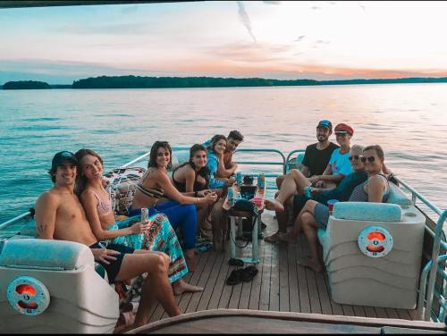A group of eight friends enjoying a sunset on a boat, smiling and relaxing by the water.