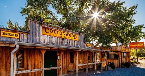 A rustic wooden steakhouse with signs for "Cottonwood Steakhouse" and "Homemade Pie," surrounded by trees and sunlight.