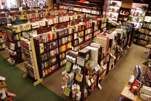 A spacious bookstore with tall shelves filled with various books and products, organized by subject.