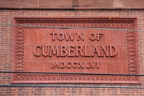 Sign on a brick wall reading "Town of Cumberland MDCCXLVI" in bold letters.