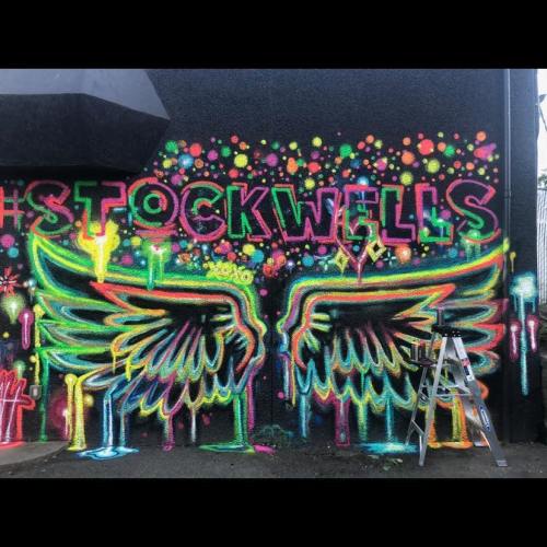 Colorful mural featuring the word "STOCKWELLS" and vibrant wings, with a ladder nearby.