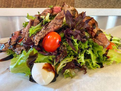 A vibrant salad topped with grilled steak, cherry tomatoes, and a creamy dressing on a bed of mixed greens.