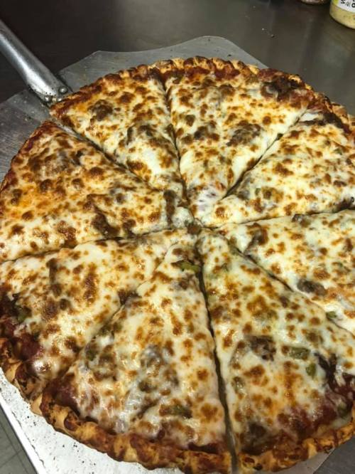 A freshly baked pizza with melted cheese and toppings, sliced into 12 pieces on a metal tray.