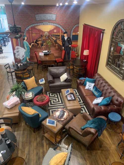 Cozy lounge area with various seating, plants, and decor, featuring a warm color palette and inviting atmosphere.