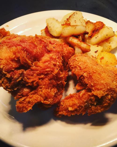 A plate of crispy fried chicken pieces served with golden-brown roasted potatoes.