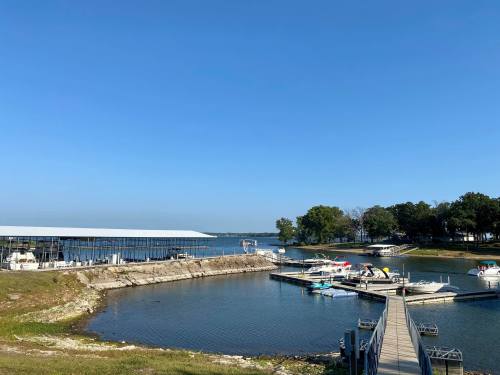 A serene lakeside view with boats docked at a marina under a clear blue sky.