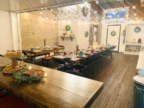 A cozy dining space with wooden tables, string lights, and festive decorations, ready for a gathering.