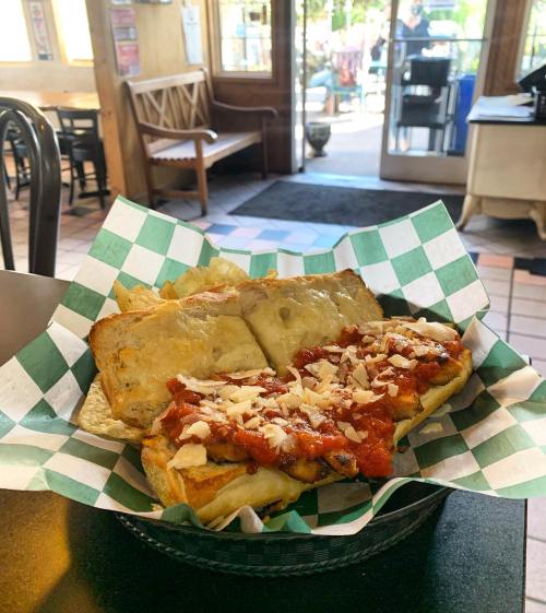 A basket of toasted sandwich with marinara sauce and cheese, served with crispy chips, in a cozy restaurant setting.