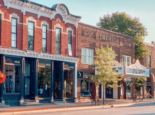 Historic buildings line a street, featuring a theater marquee and storefronts with decorative architecture.