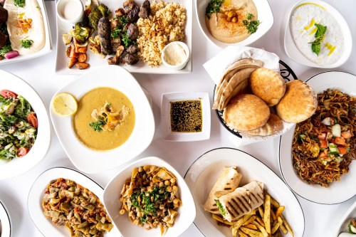 A variety of dishes including rice, grilled meats, salads, and sauces arranged on a table.