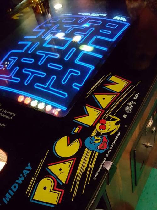 Close-up of a Pac-Man arcade game, featuring the colorful logo and illuminated game screen.