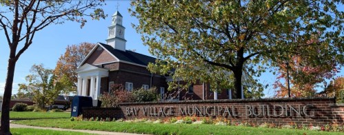 Bay Village Municipal Building with a clock tower, surrounded by colorful autumn trees and a clear blue sky.