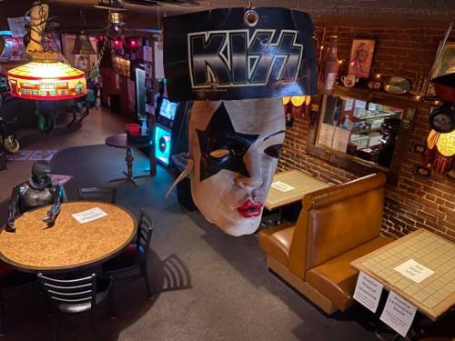 A hanging KISS mask in a lively bar with tables and decor in the background.