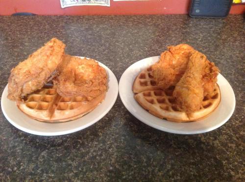 Two plates of fried chicken served on waffles, one with two pieces of chicken and the other with three pieces.