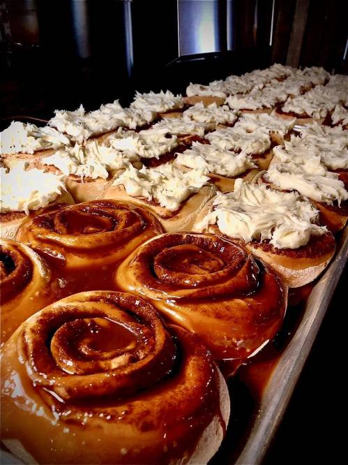 A tray of freshly baked cinnamon rolls topped with creamy frosting, showcasing a delicious, gooey caramel glaze.