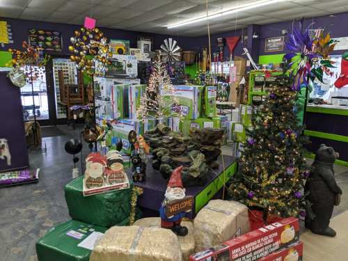 A colorful store display featuring holiday decorations, a small tree, and various garden items.