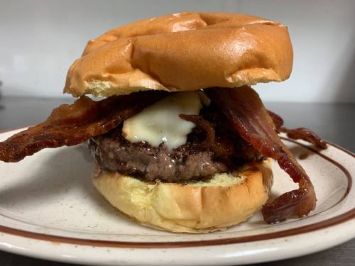 A juicy burger with bacon and mayonnaise, served on a toasted bun on a plate.