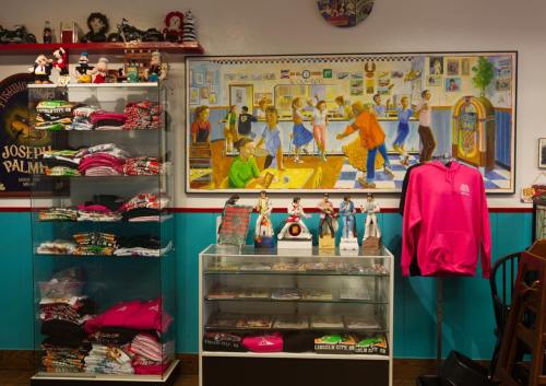 A colorful shop interior featuring merchandise displays and a mural of people dancing in a diner setting.