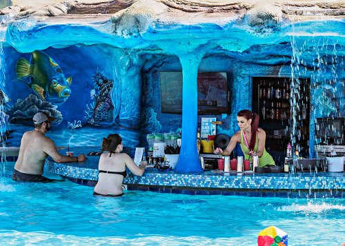 A colorful pool bar scene with two customers and a bartender, surrounded by vibrant underwater-themed murals.