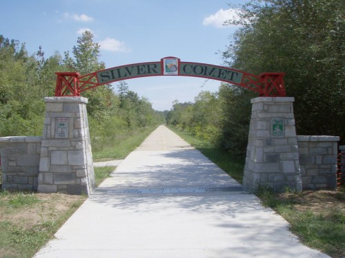 Entrance to the Silver Comet Trail, featuring a red archway and a paved path surrounded by greenery.