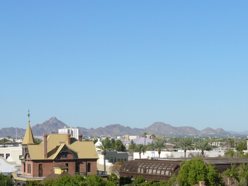 A clear blue sky over a cityscape featuring mountains in the background and historic buildings in the foreground.