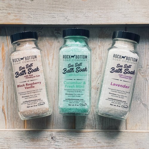 Three bottles of sea salt bath soak in flavors: Black Raspberry Vanilla, Cucumber & Fresh Mint, and Lavender.