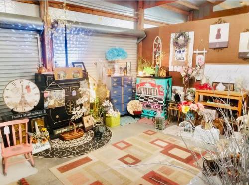 A cozy vintage shop display featuring eclectic furniture, decor, and plants in a warm, inviting setting.