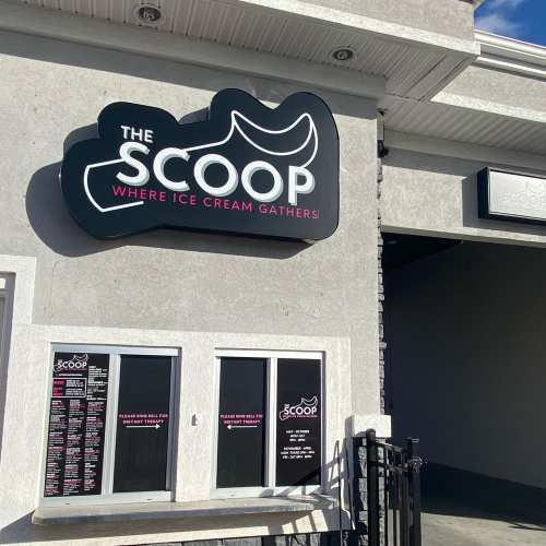 Sign for "The Scoop" ice cream shop, featuring a playful logo and menu displayed on the wall.