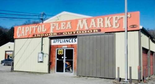 Exterior of Capitol Flea Market building with a large sign, featuring "Indoor-Outdoor" and "Appliances" above the entrance.