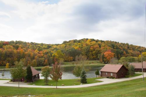 Scenic view of a lake surrounded by colorful autumn trees and rustic cabins along a winding path.