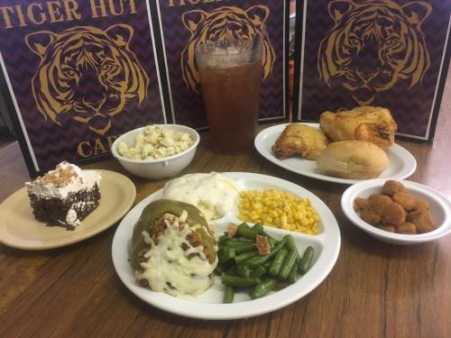 A plate of food featuring stuffed peppers, green beans, corn, popcorn, fried chicken, rolls, and dessert, with drinks.