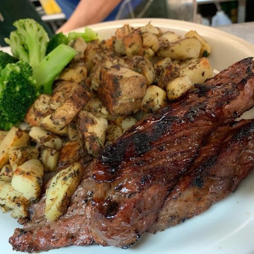 A plate of grilled steak with seasoned roasted potatoes and steamed broccoli.