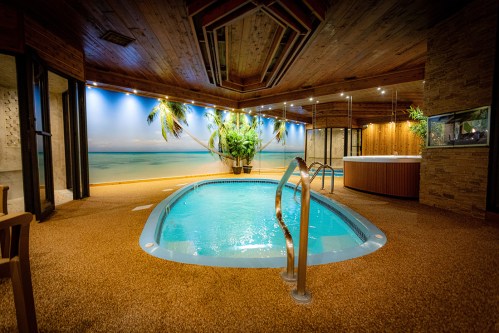 Indoor pool area with tropical decor, wooden ceiling, and a relaxing atmosphere.