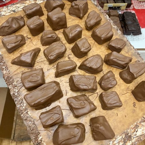 A tray of assorted chocolate-covered candies in various shapes and sizes, arranged neatly on a parchment-lined surface.