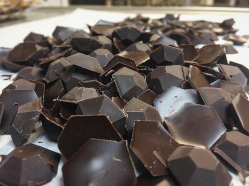 A close-up of irregularly shaped dark chocolate shards scattered on a surface.