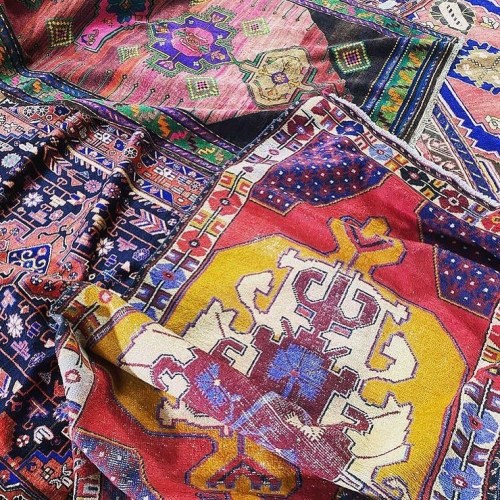 A vibrant display of colorful, intricately patterned textiles and rugs arranged together.