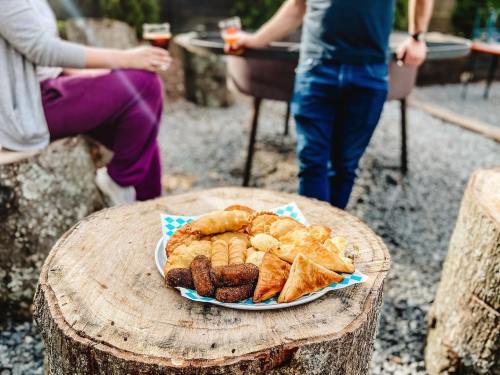 A wooden stump holds a plate of assorted pastries, while people enjoy drinks in the background.