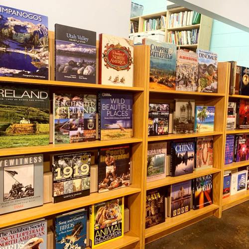 Bookshelves filled with various books on topics like travel, history, and nature in a cozy bookstore setting.