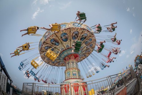 A colorful swing ride at an amusement park, with riders suspended in the air against a blue sky.