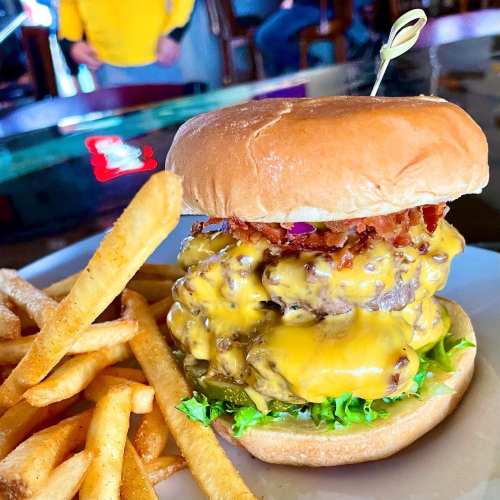 A juicy cheeseburger stacked with melted cheese and bacon, served with crispy fries on the side.