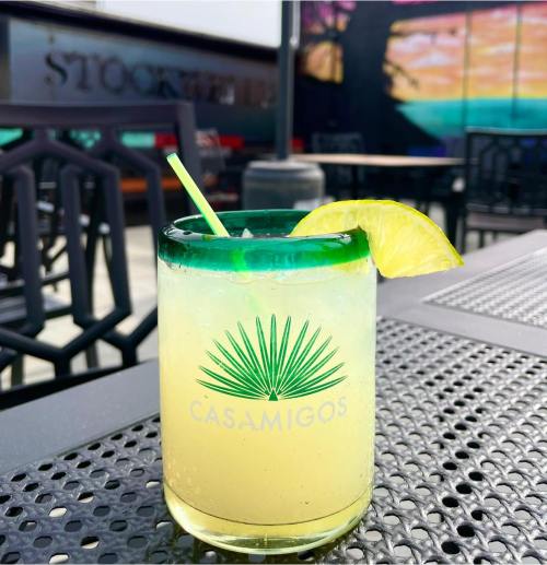 A refreshing Casamigos cocktail with a lime wedge and straw, set on a textured outdoor table.