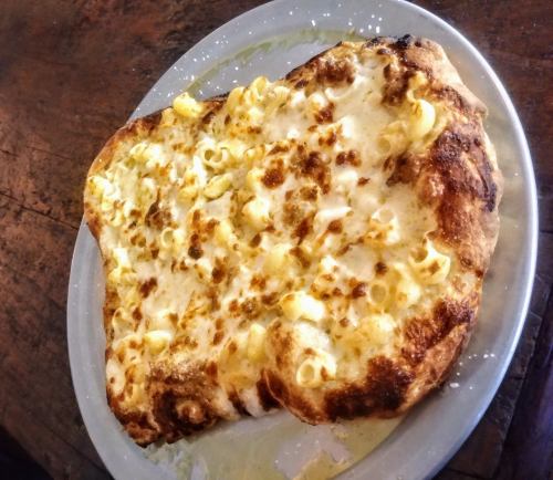 A plate of pizza topped with macaroni and cheese, featuring a golden, crispy crust.