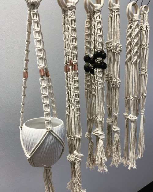 A collection of macramé plant hangers in various styles, featuring a white ceramic pot and decorative beads.