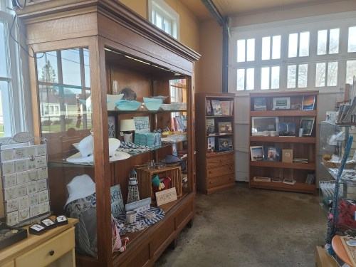 A cozy shop interior featuring wooden display cases filled with various items, including books, accessories, and decor.