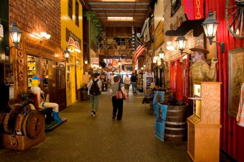 A vibrant indoor market with colorful shops, wooden decor, and visitors walking through the bustling space.