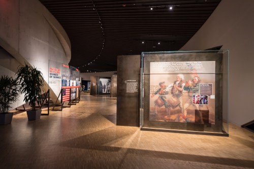 A modern museum interior featuring exhibits with text panels and a glass display case in a spacious, well-lit area.